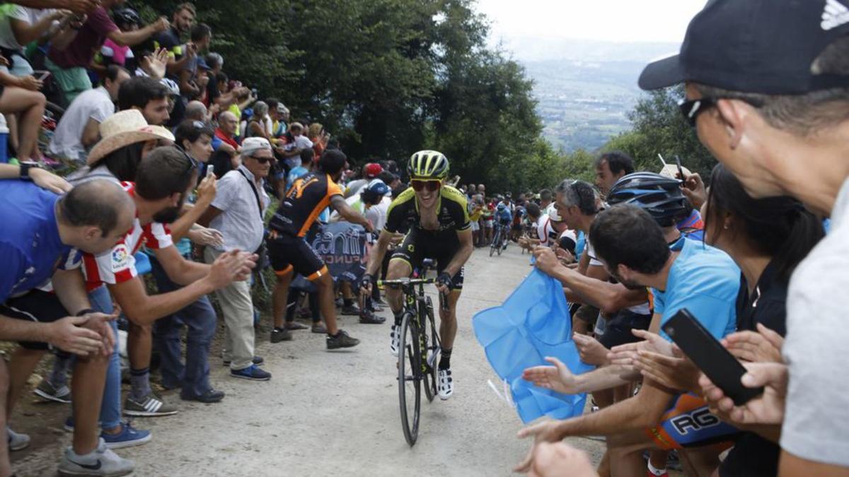 Un ciclista, rodeado de aficionados, durante el ascenso a Les Praeres (Peñamayor) de la Vuelta a España. 