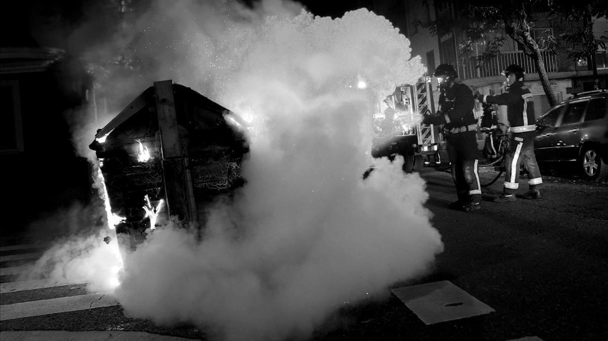 Un bombero apaga un contenedor de basura incenciado durante las protestas en Burgos.