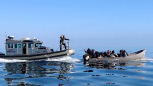 Guardacostas tunecinos intentan detener el avance de un bote con migrantes que intentan llegar a Italia.