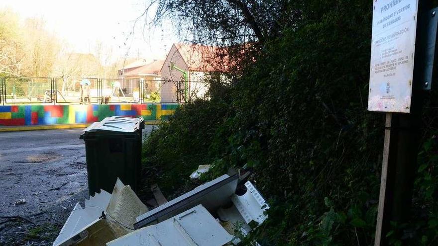 Escombros depositados frente al colegio A Rúa junto a un cartel que lo prohíbe. // G.Núñez