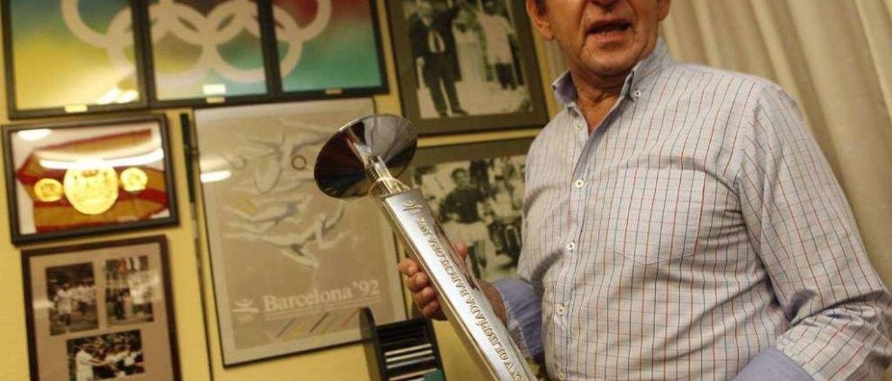 Agustín Antuña, con su colección de objetos olímpicos y en la mano la antorcha olímpica que él portó.