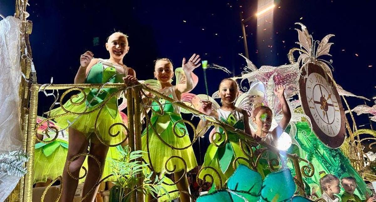 Unas niñas lanzan pétalos de flores en las carrozas de Marín.