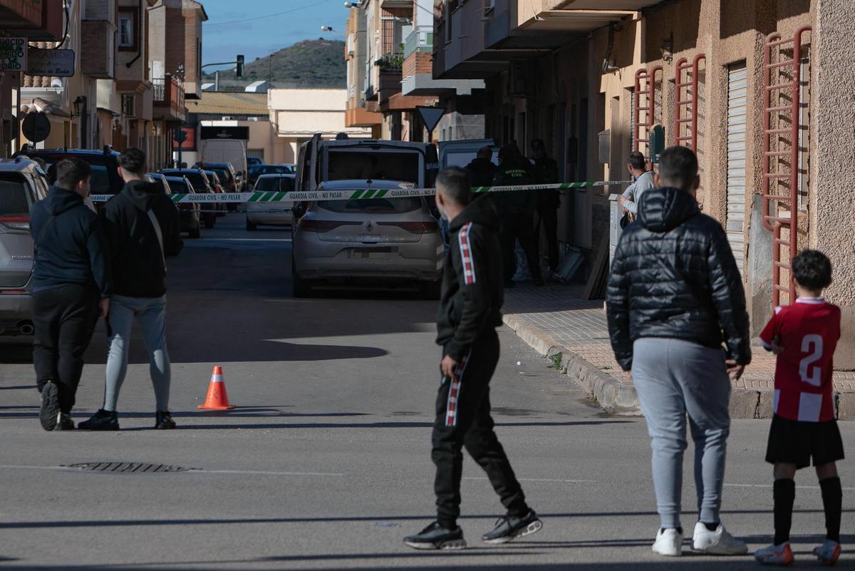 Un grupo de viandantes mira la calle de El Algar, acordonada, donde se cometió el primer crimen de 2026 en la Región.