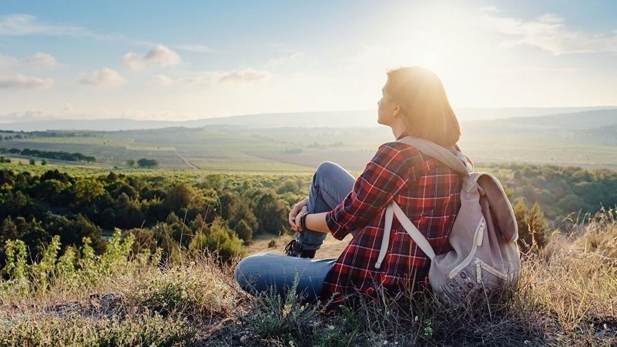 Una mujer contempla la puesta de sol desde una colina.