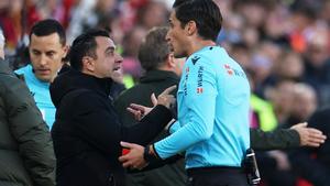 Xavi Hernández y José Luis Munuera Montero durante el partido