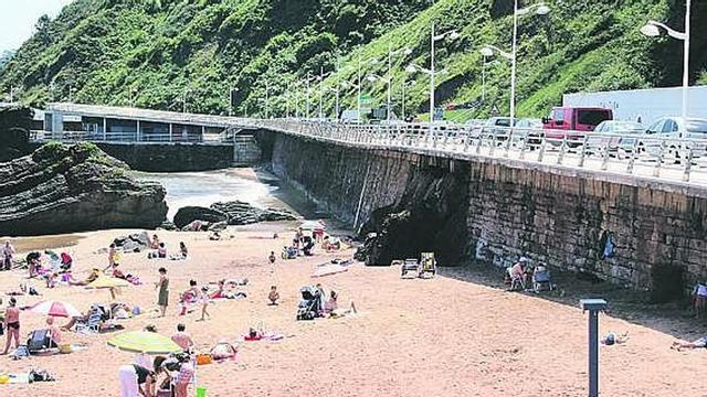 Veraneantes en la playa de Candás, este fin de semana, con el aparcamiento habilitado lleno.