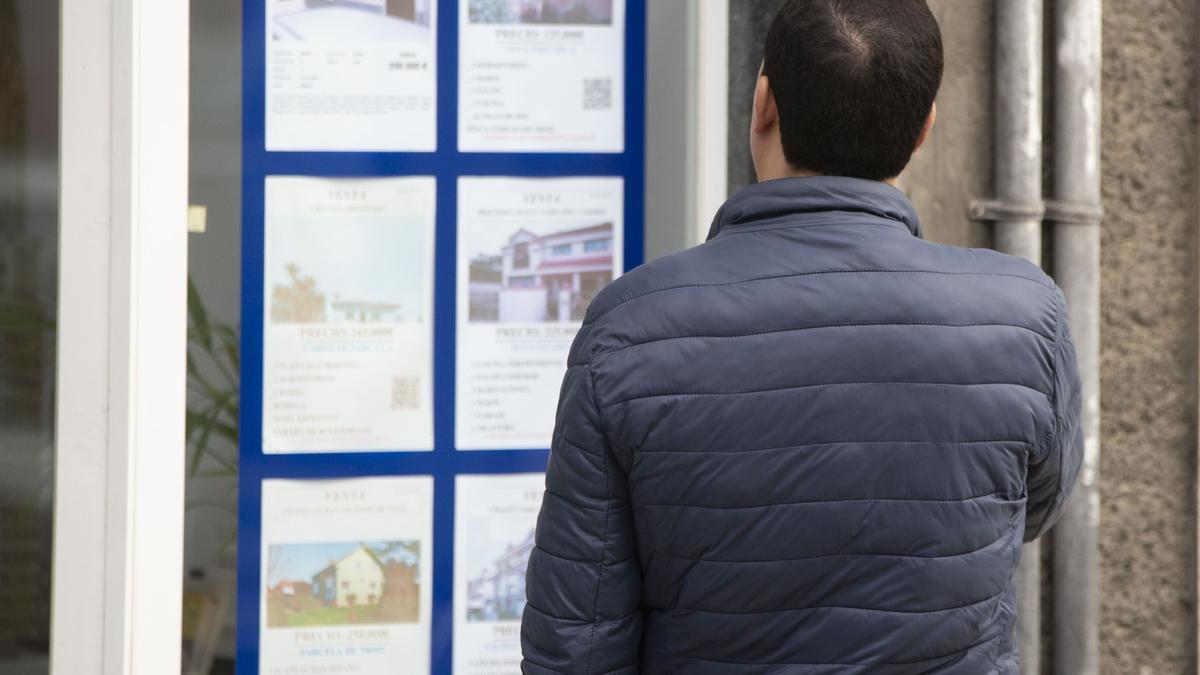 Una persona consulta los carteles de una agencia inmobiliaria.