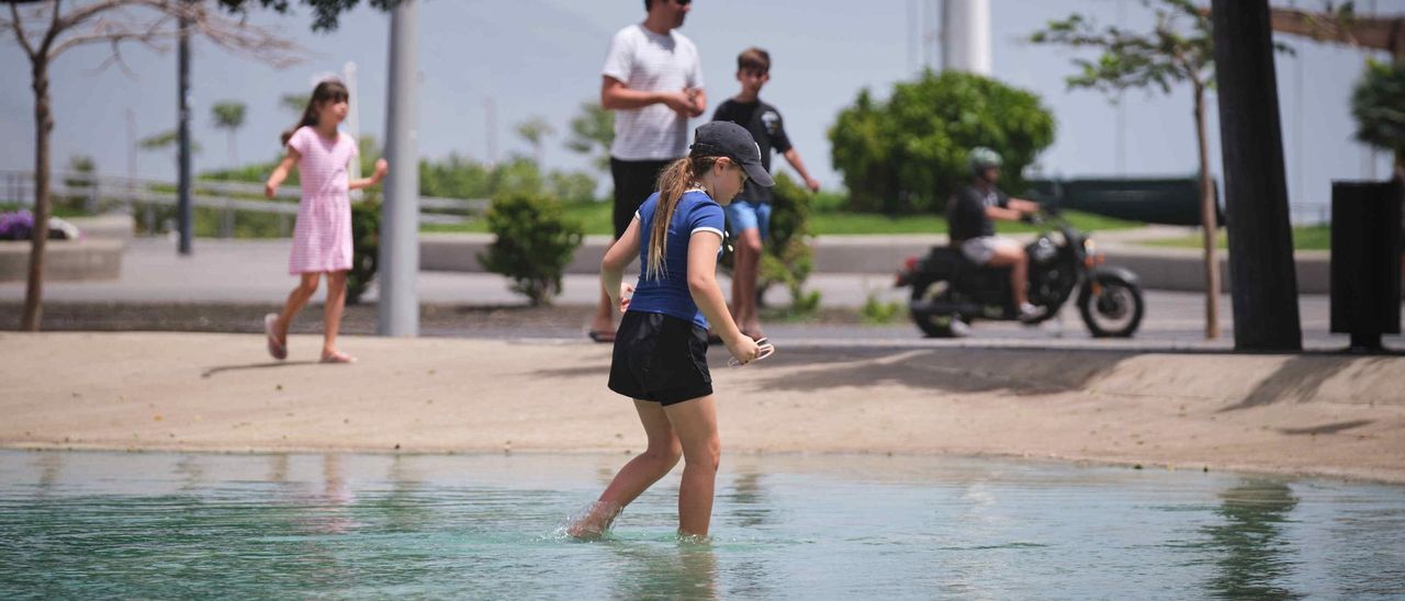 Una niña se refresca del calor en el lago de Plaza de España.