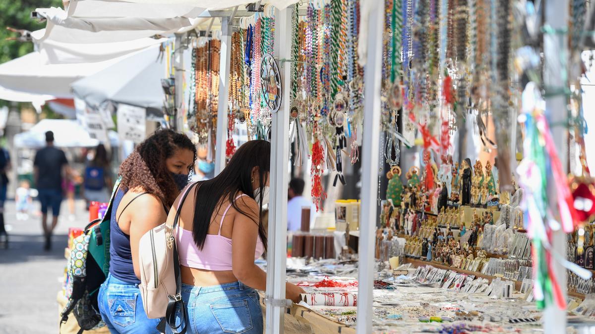 Dos visitantes revisan los productos de un puesto del mercadillo de Teror en agosto