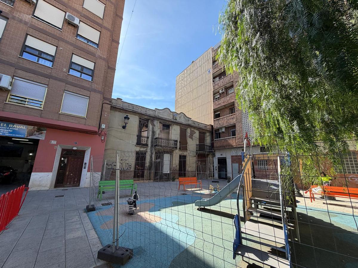 El parqu einfantil vallado frente a la vivienda en ruinas.