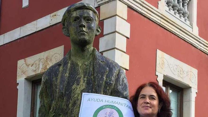 Rosa María Sacristán muestra el logo de Alendar junto a la escultura &quot;El emigrante&quot; en Cangas de Onís.