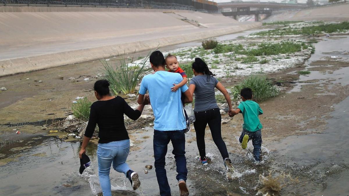 Un bebé, un niño y varios adultos inmigrantes cruzan la frontera entre México y EEUU para ingresar en Tejas.