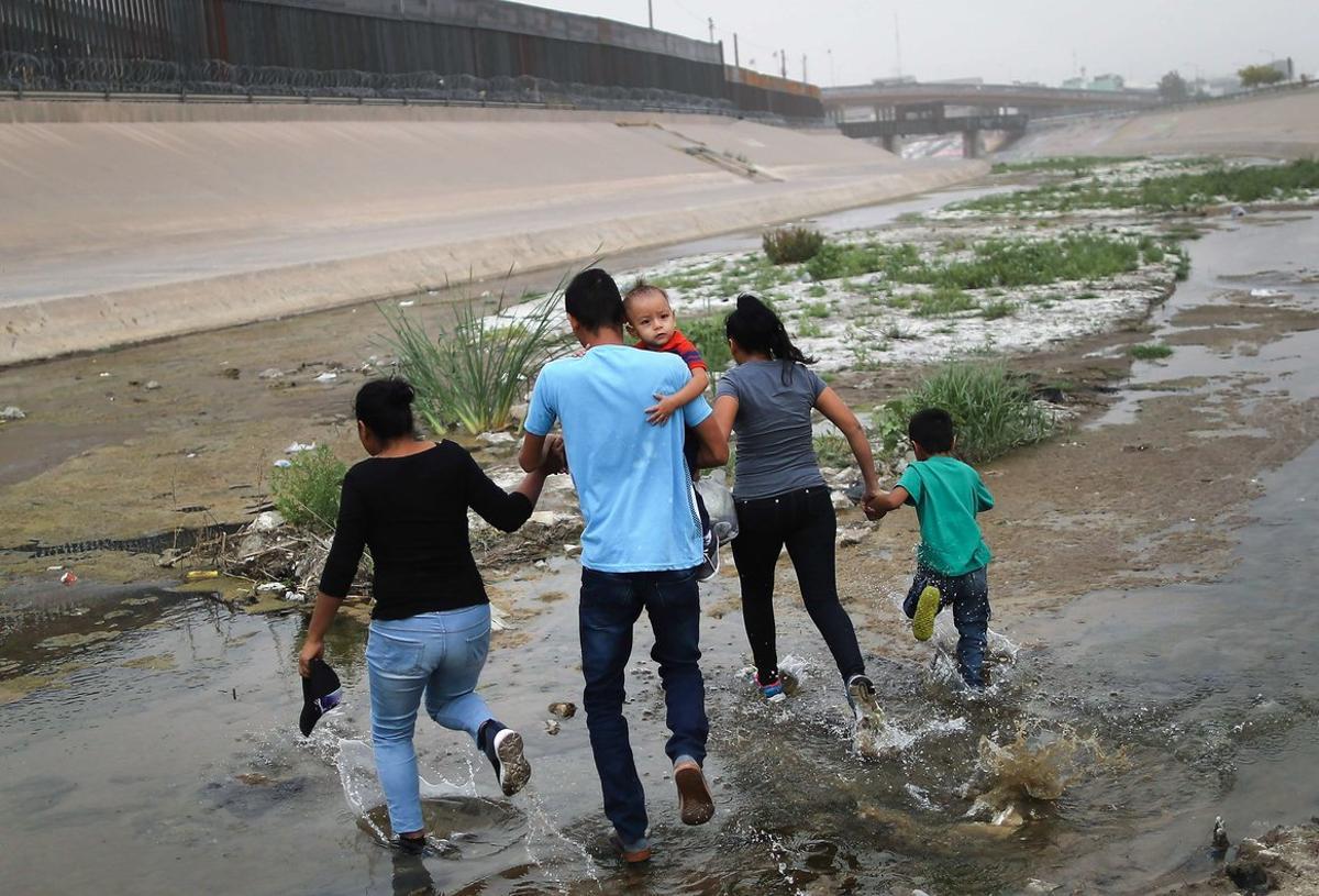 CIUDAD JUAREZ, MEXICO - MAY 20: Migrants hold hands as they cross the border between the U.S. and Mexico at the Rio Grande river, on their way to enter El Paso, Texas, on May 20, 2019 as taken from Ciudad Juarez, Mexico. The location is in an area where migrants frequently turn themselves in and ask for asylum in the U.S. after crossing the border. Approximately 1,000 migrants per day are being released by authorities in the El Paso sector of the U.S.-Mexico border amidst a surge in asylum seekers arriving at the Southern border.   Mario Tama/Getty Images/AFP