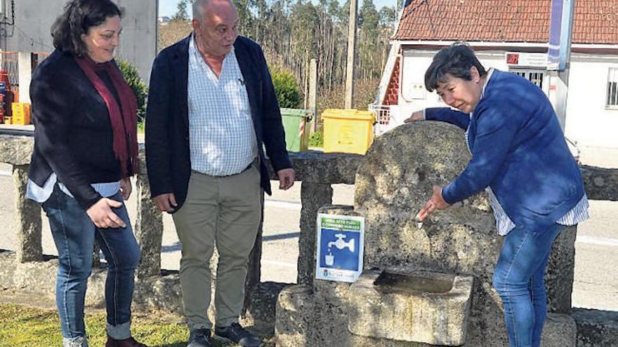 El alcalde Andrés Iglesias y las concejalas Blanca Míguez y Dolores Santoro, en la fuente recién señalizada en la plaza del Concello. // FdV