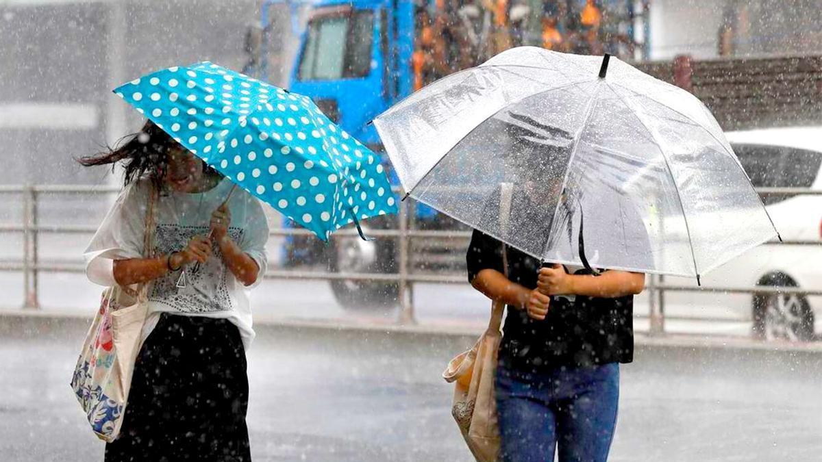 Dos peatones protegiéndose de la lluvia.