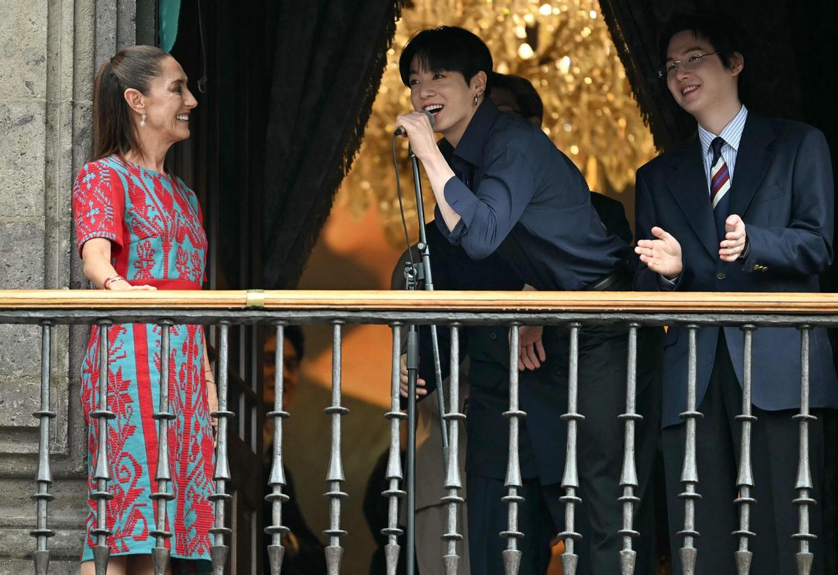(De izquierda a derecha) Jung Kook (C) y Suga (D) del grupo surcoreano de K-pop BTS saludan a los fans junto a la presidenta de México, Claudia Sheinbaum (I), desde el balcón.