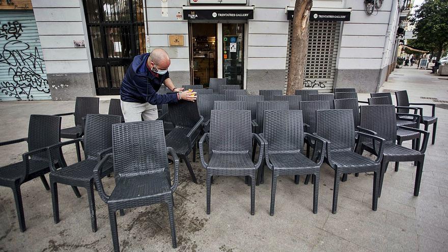 El propietario de un bar de Russafa limpia las sillas de su terraza horas antes de la comparecencia de ayer de Ximo Puig. | F. BUSTAMANTE