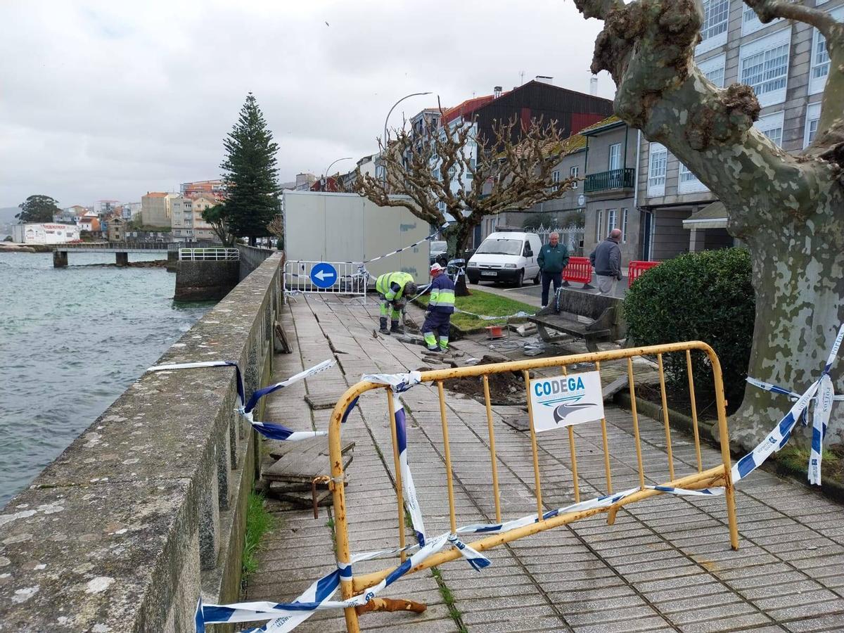 Los operarios trabajando ayer en Pescadoira para levantar el pavimento del paseo.