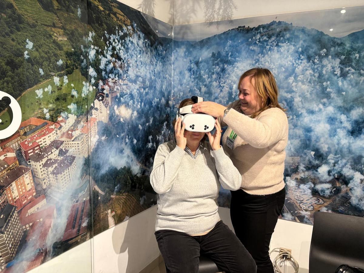 Carmen Rodríguez ayuda a poner les gafes de realidá virtual a una de les visitantes de les xornaes de puertes abiertes celebraes en Navidá.