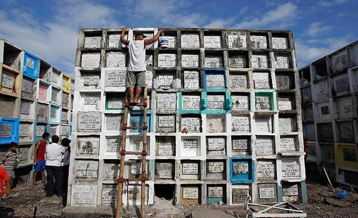 Un home neteja la tomba del seu fill al cementiri públic de Navotas, a Manila.