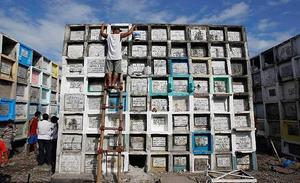 Un home neteja la tomba del seu fill al cementiri públic de Navotas, a Manila.