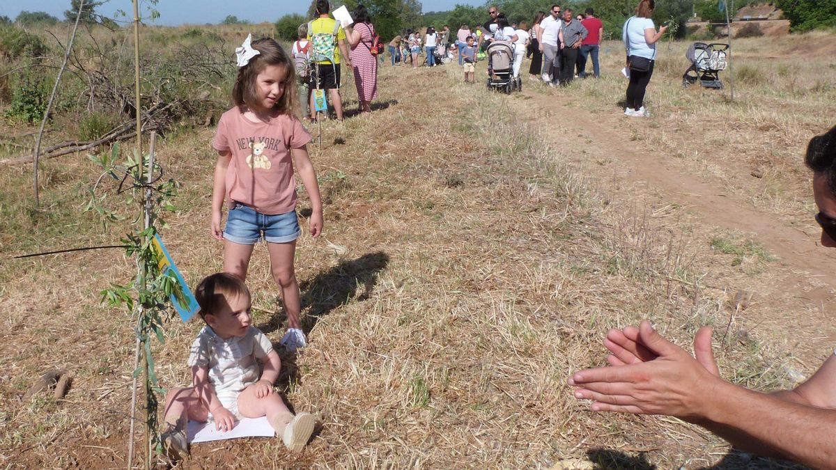 El pequeño Adrián, acompañado por su hermana Lucía, sentado junto a su árbol