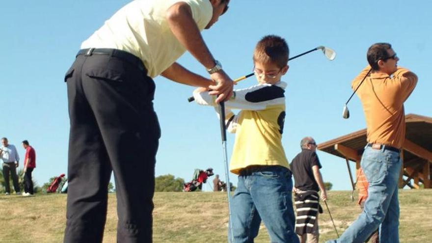 Un niño aprende a jugar al golf en una foto de archivo.