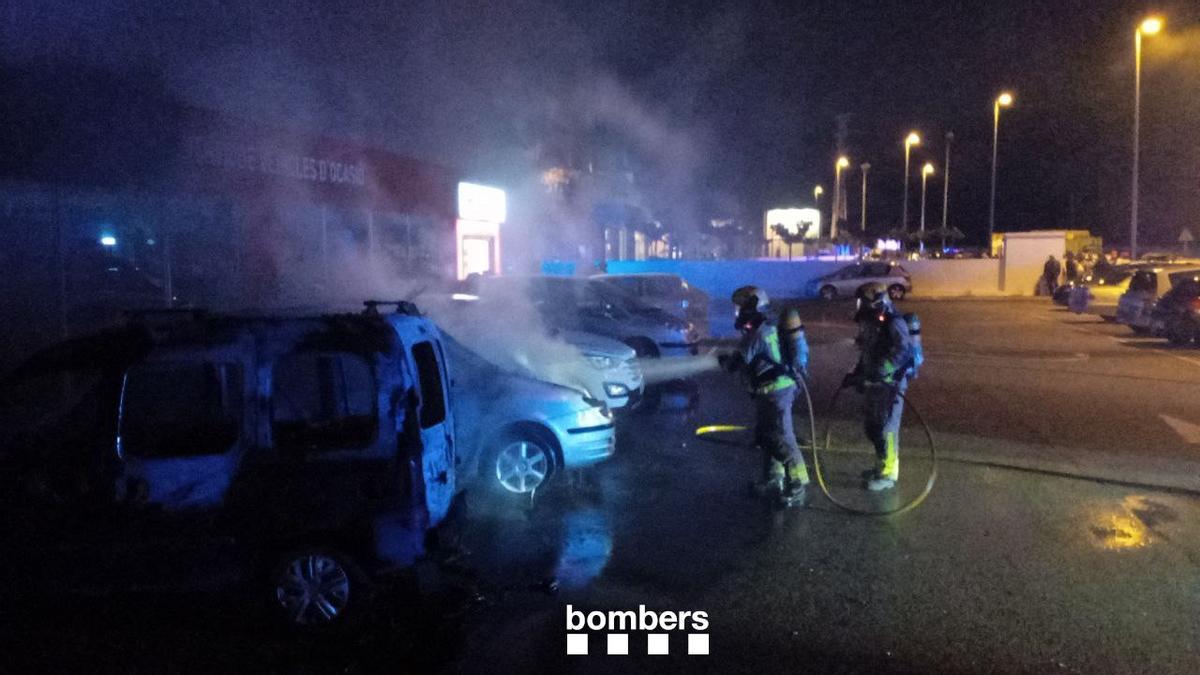 Els Bombers extingint els vehicles afectats a l'exterior del concessionari de Figueres.