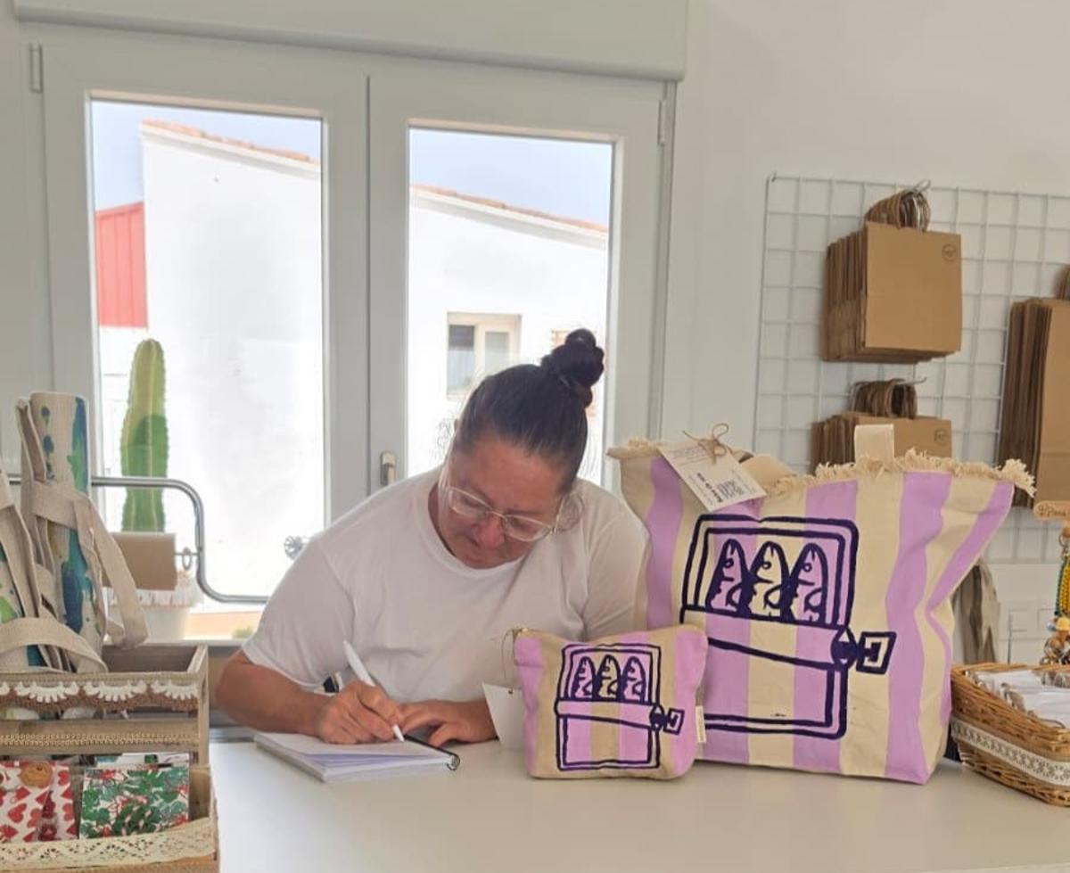 Elisa en la caja apuntando en su libreta.