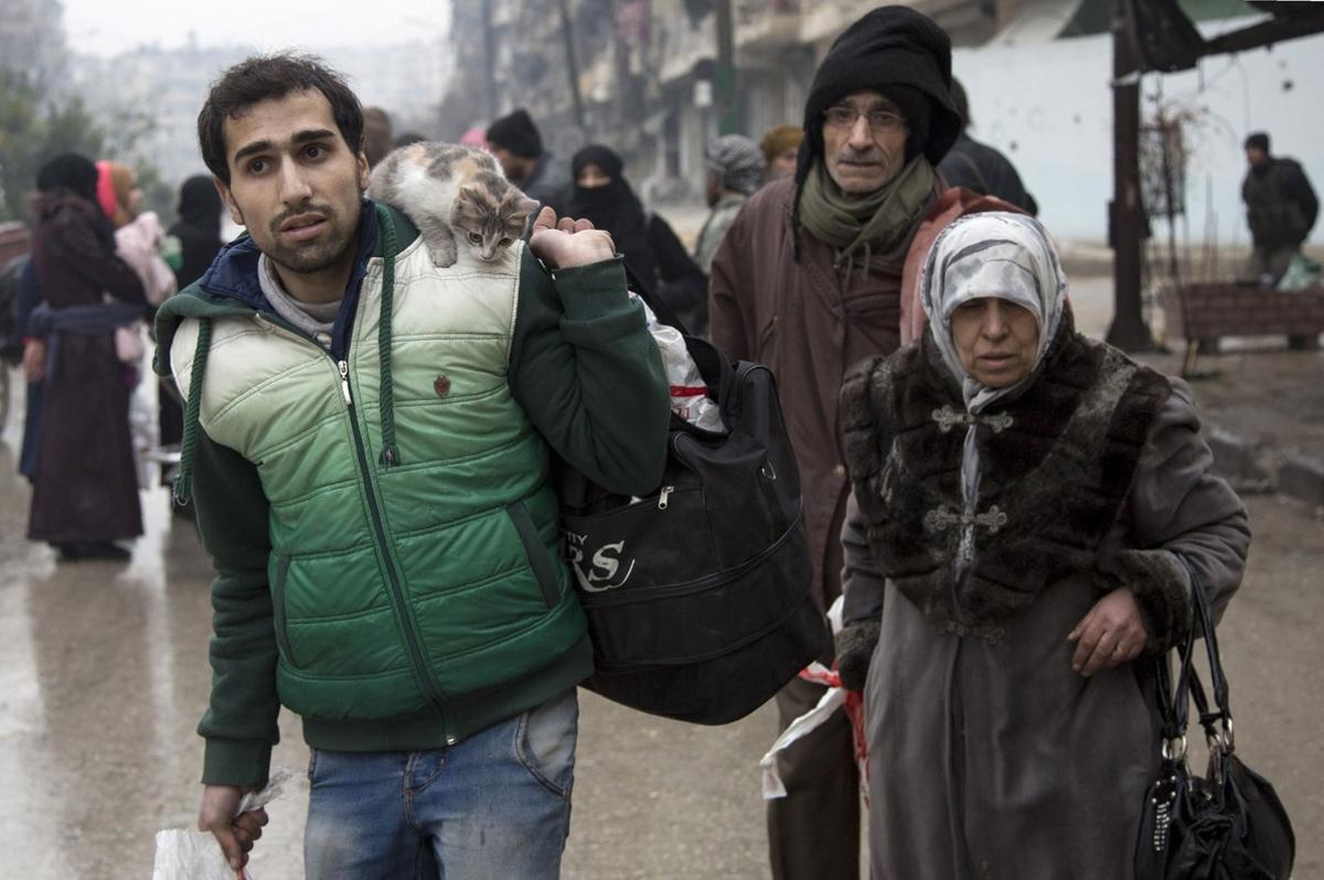 TOPSHOT - Syrians leave a rebel-held area of Aleppo towards the government-held side on December 13, 2016 during an operation by Syrian government forces to retake the embattled city.