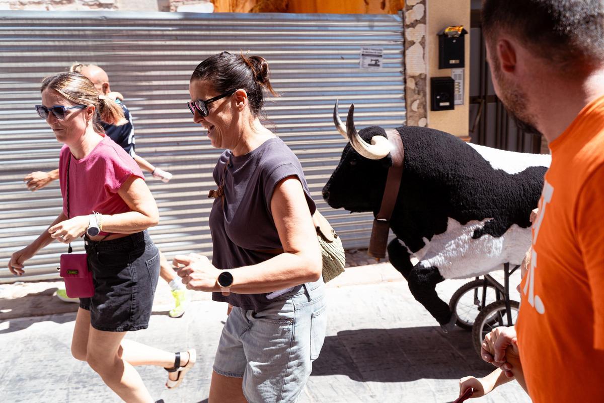Unas vecinas corren delante de un carretón  taurino de los encierros infantiles.