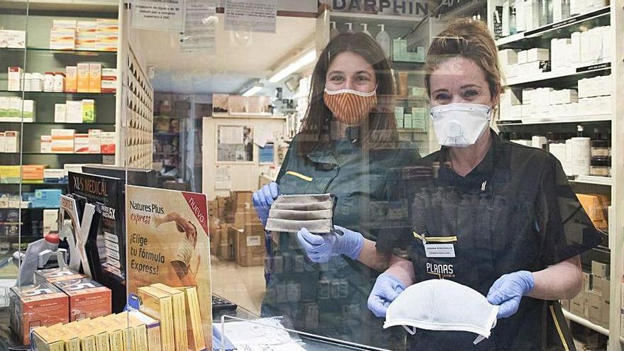 Treballadores de la farmàcia Planas, al carrer Guimerà, mostrant algunes de les mascaretes, ahir