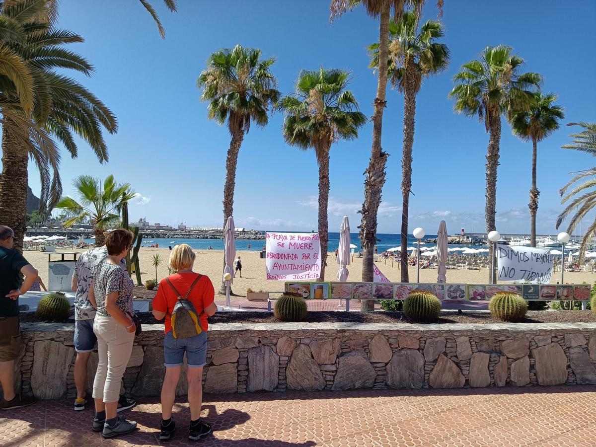 Unos turistas observan las pancartas que Pablo González ante sus restaurantes a modo de protesta.