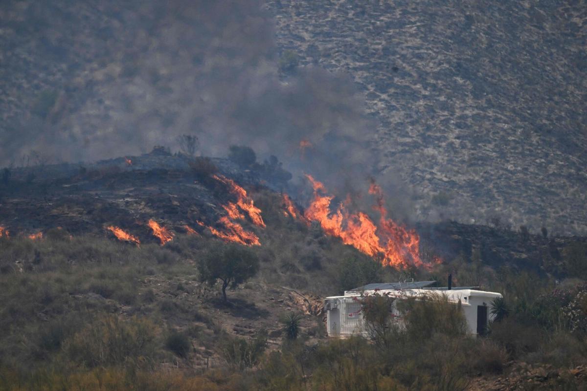 Una foto tomada el 10 de julio de 2026 muestra llamas en una colina junto a una casa, en el área de un incendio forestal que mató a 11 cerca de Bedar, en el distrito de Los Gallardos, en la provincia de Almería.