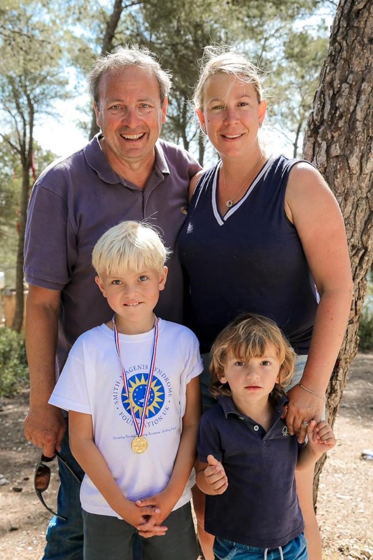 Theo, con camiseta blanca y la medalla, con sus padres y su hermano.