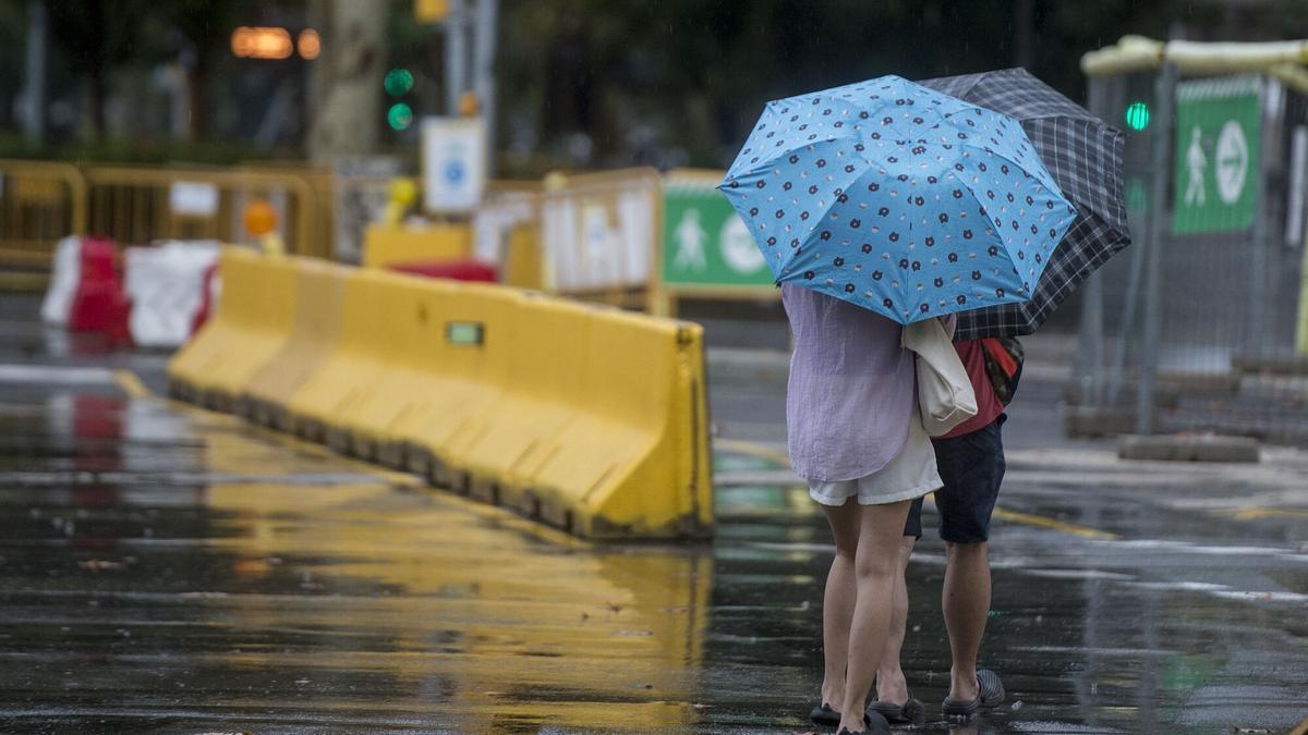 Gente con paraguas bajo la lluvia por el paseo de Sant Joan.