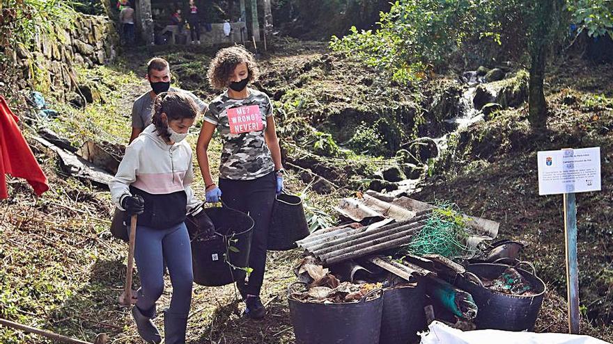 Unos voluntarios en la jornada de limpieza del río Maceiras.   | // R. GROBAS