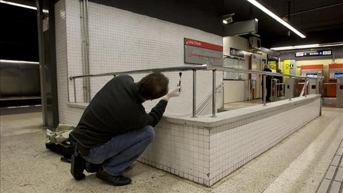 Un mosso recoge huellas dactilares en el lugar donde fue apuñalada una persona, en el metro de Barcelona. 