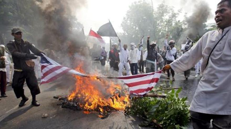 Manifestantes sostienen una bandera estadounidense en llamas durante una protesta en Yakarta.