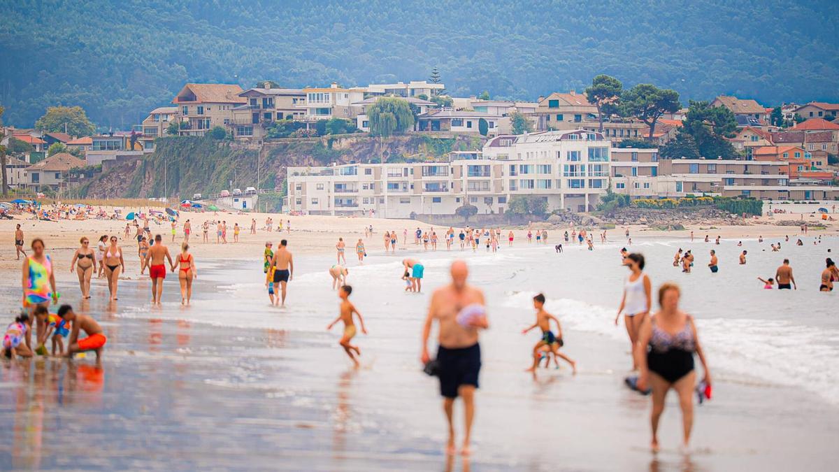 Gente bañándose y disfrutando este viernes de la playa de Samil.