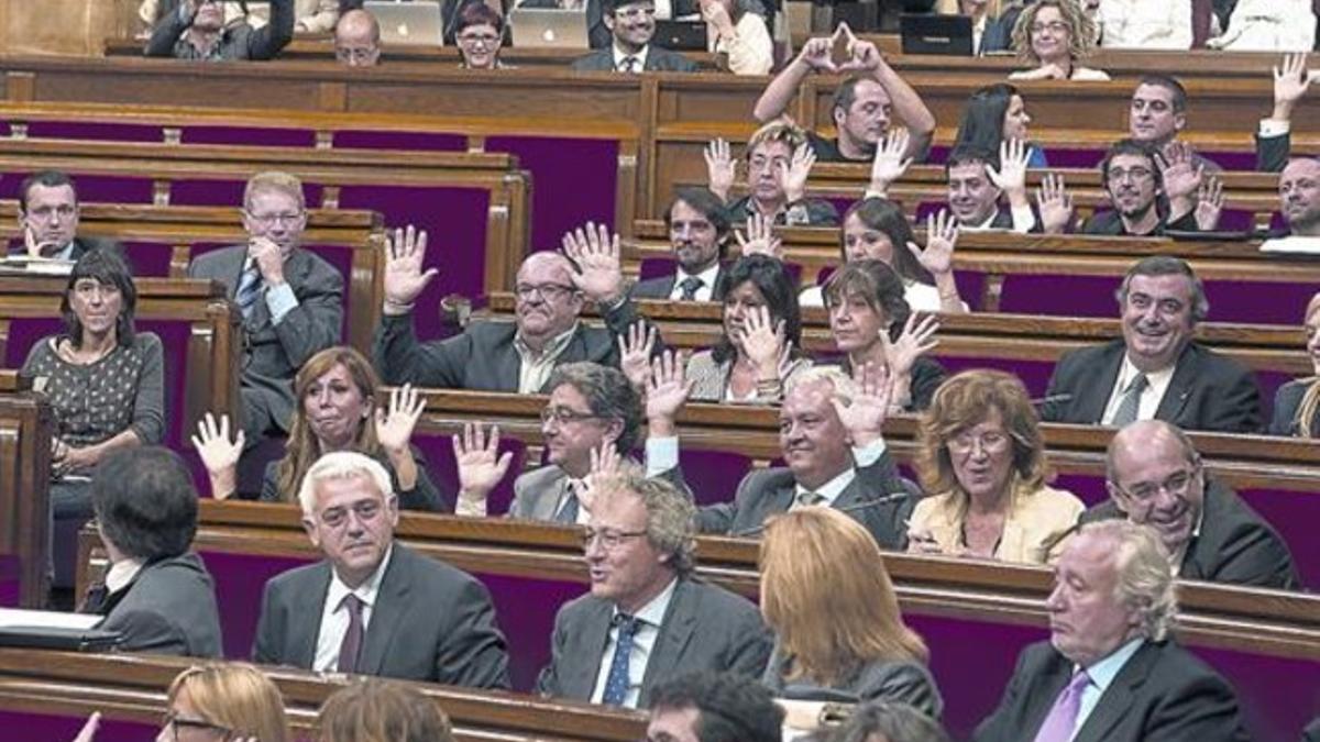 Los diputados del PP alzan las manos para mostrar que no pulsan ningún botón en la votación. Al fondo, Fernández (CUP) hace el símbolo feminista.