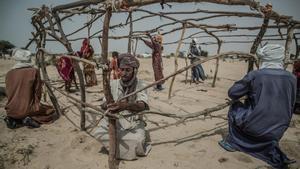 Un grupo de desplazados construye una cabaña en el asentamiento de Manara.