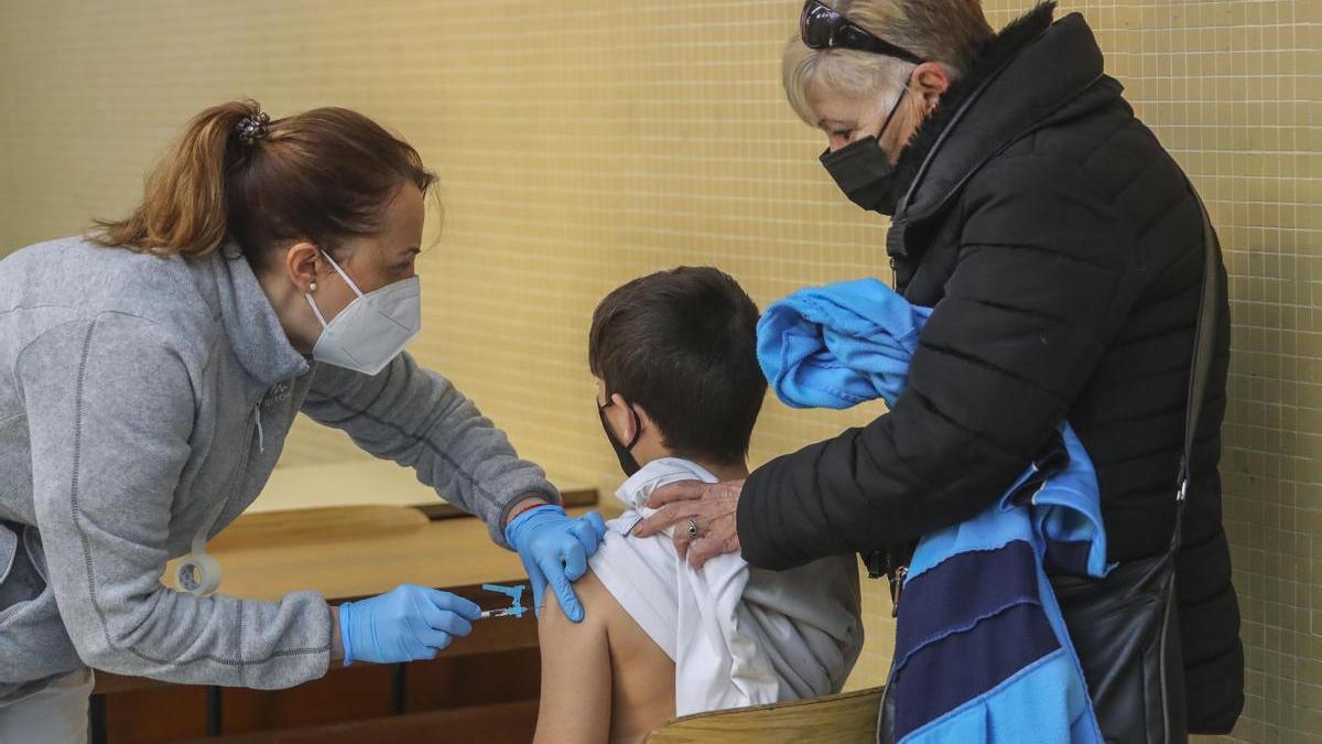Un alumno recibe la primera dosis de su vacuna contra el coronavirus en un colegio acompañado por un familiar el pasado mes de diciembre.