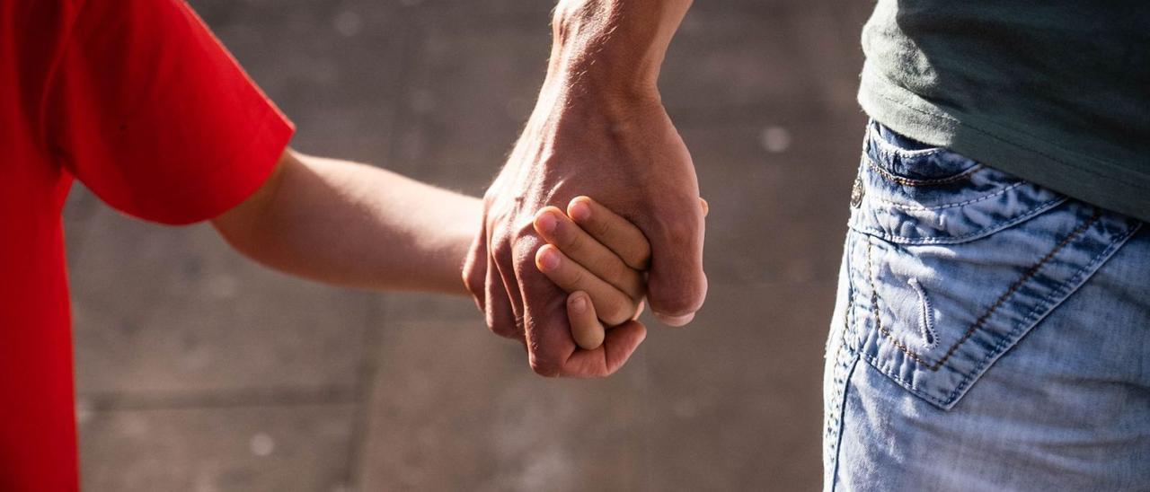 Un hijo y un padre caminan de la mano. | |