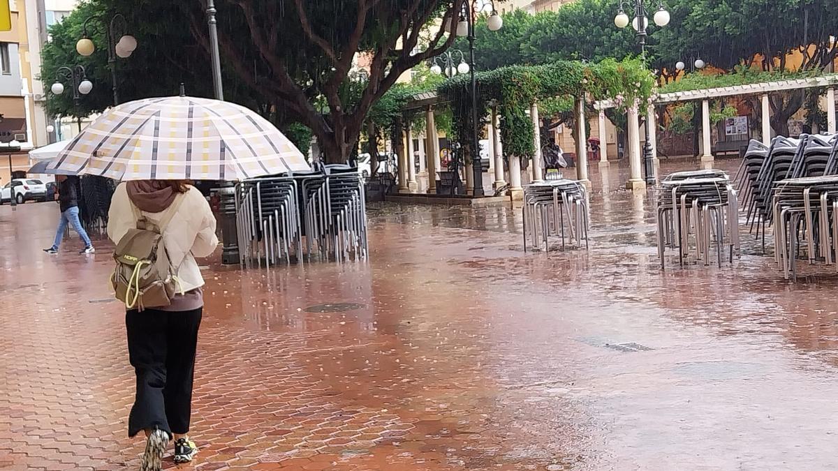 Una mujer se resguarda de la lluvia bajo su paraguas, en Alzira.