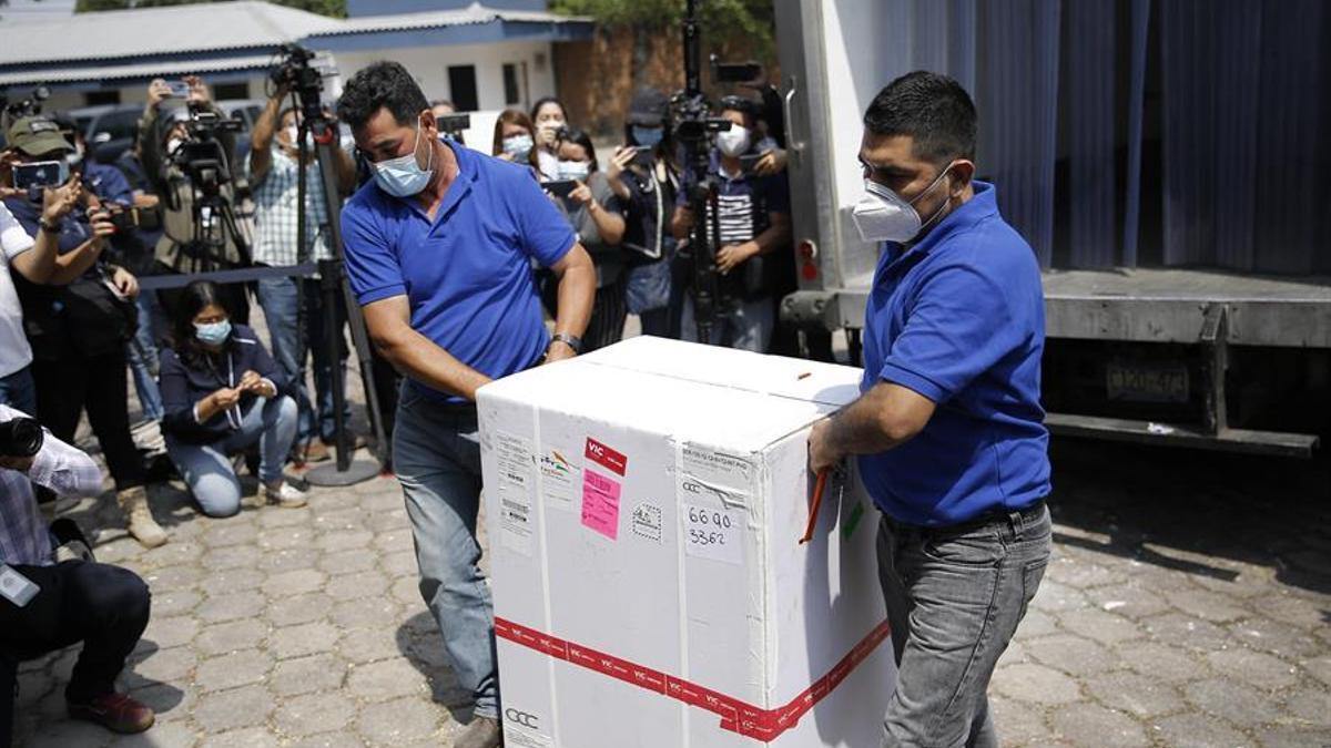 Dos hombres bajan de un camión una caja que contiene dosis de las vacunas contra el covid-19.