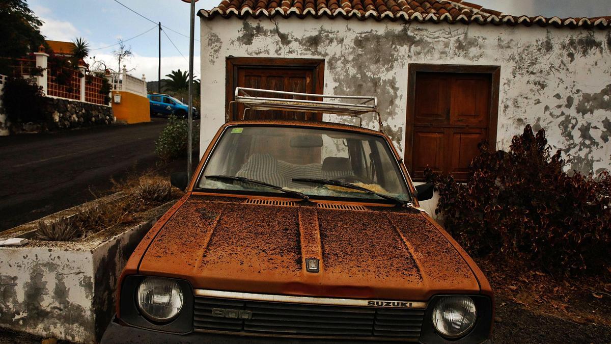 Una casa y un vehículo recubiertos de arena del volcán, en La Palma. | | AGENCIAS