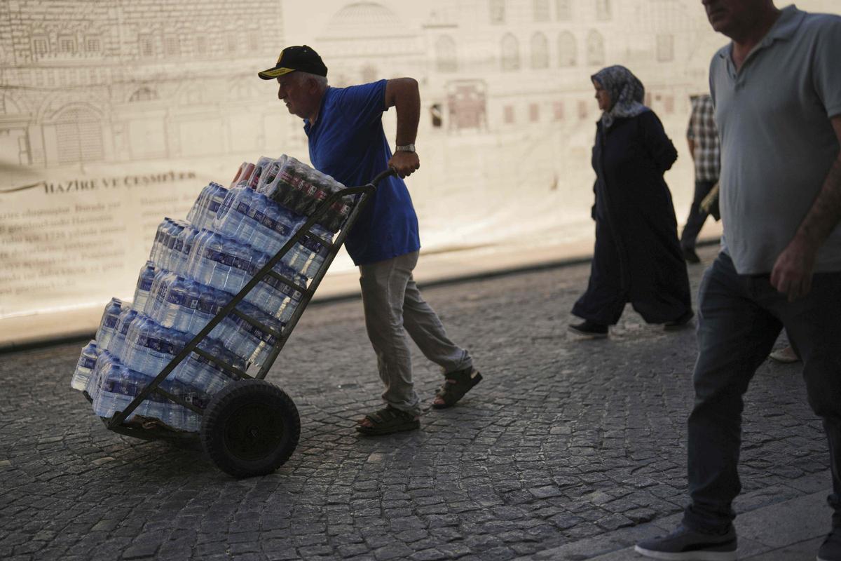 Un repartidor con una carretilla cargada con botellas de agua, este viernes en Estambul.