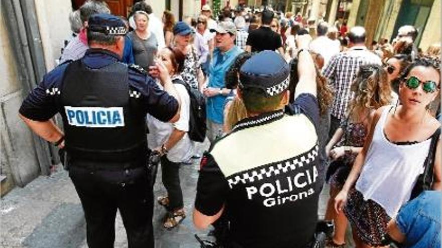 Dos agents armats dirigint el públic al mig del carrer, durant Temps de Flors.