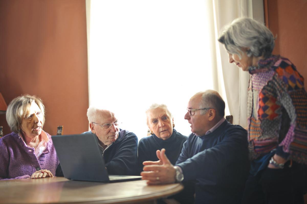 Un grupo de personas mayores frente a un ordenador. 